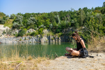 Girl sitting with a book near the lake