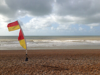red yellow flag on a windy beach - 387424190