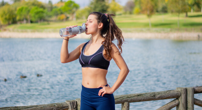 Instructor de fitness mujer delgada hermosa cauc&aacute;sica agua potable durante los ejercicios de entrenamiento al aire libre. mujer en ropa deportiva