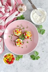 Canape or crostini with toasted bread, light cheese and colorful bell pepper. Top view with copy space.