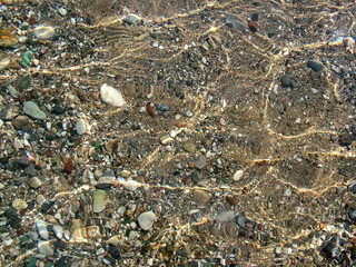 Pebbles on the beach in water of the Mediterranean