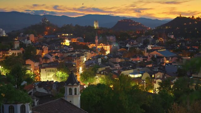 Evening view of Plovdiv old town, Bulgaria. Old illuminated houses and sunset sky. Zoom out shot. View from Nebet Tepe hill Plovdiv city canter. 4K