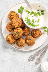 Homemade falafel close up. Chickpea balls with spices and yogurt with herbs on a gray concrete table.