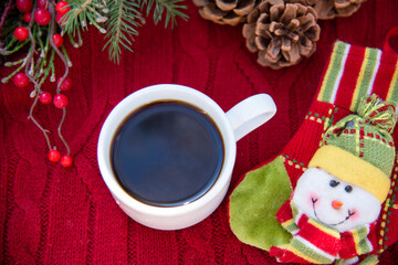 Coffee Cup on red knitted background with Christmas decorations