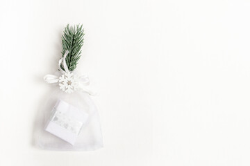 Xmas festive minimal backdrop with trendy Christmas small diy gift in mesh pouch and reusable decor on white backdrop.