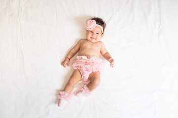 Shirtless baby girl lying on bed at home