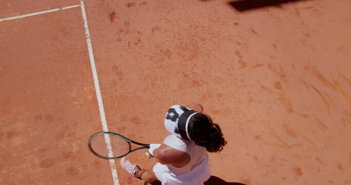 Woman serving ball during tennis match on clay court