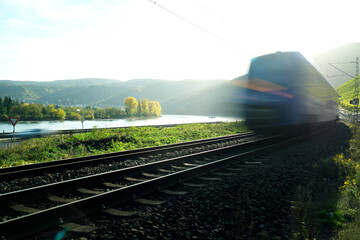 Gegenlichtaufnahme mit Bewegungsunschärfe von herannahendem Zug auf der Bahnstrecke zwischen Mainz...