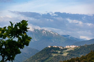 Beautiful landscape of mountains in the clouds and the city, which is located in the lowlands. Peaks in the clouds. Spectacular view.