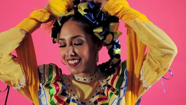 Joven mujer mexicana latina en traje regional folclórico en fondo rosa