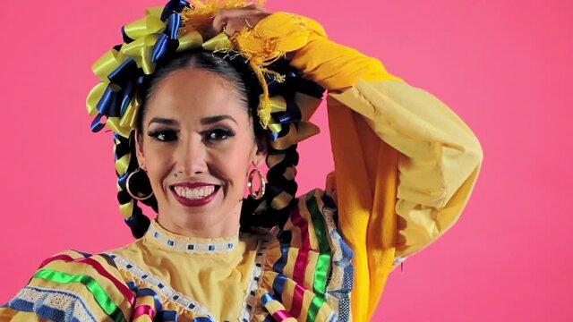 Joven mujer mexicana latina en traje regional folcl&oacute;rico en fondo rosa
