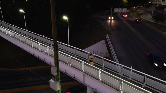 Toma a&eacute;rea de joven atl&eacute;tica mexicana corriendo en puente sobre trafico de la ciudad de noche