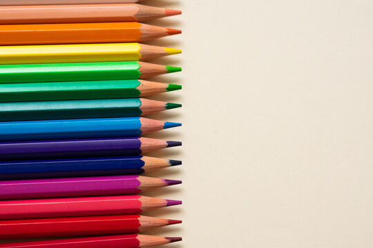 Color pencils all ordered in a gradient, on the left side of the image, with the right side full of copy space
