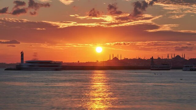 Amazing sunset in Istanbul, Turkey. Sun is setting down behind silhouettes of Hagia Sophia and Blue Mosque. Sunset landscape panorama time lapse taken from Kadikoy Istanbul, Turkey