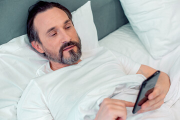 Calm man browsing the Internet after waking up