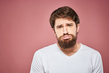Obraz premium Emotional bearded man in white T-shirt discontent pink background