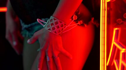 Go-Go show and Striptease slender woman in short denim shorts her thighs close up, behind her glowing lettering. She stands and poses.