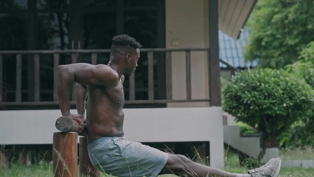 Young african american fit man doing dips on parallel bars at an outdoor gym park