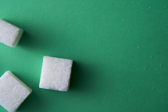 top view of white sugar cube on green background