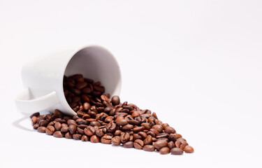 Isolated coffee beans (selective focus on coffee beans) with ceramic cup, white background.