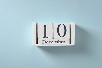 Wooden white calendar on blue background, date 10 December.