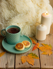 Obraz na płótnie Canvas cup of tea and cookies on table with yellow autumn leaves and candles at cozy table 