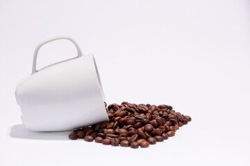 Isolated coffee beans (selective focus on coffee beans) with ceramic cup, white background.