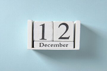 Wooden white calendar on blue background, date 12 December.