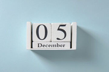 Wooden white calendar on blue background, date 5 December.