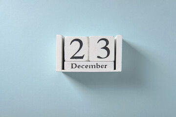 Wooden white calendar on blue background, date 23 December.