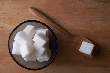 top view of bowl of white sugar cube   with wooden spoon