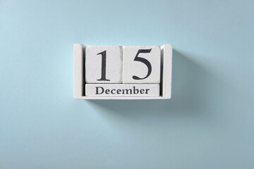 Wooden white calendar on blue background, date 15 December.