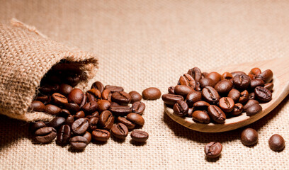 roasted coffee beans on wooden spoon, (selective focus on coffee beans), raffia sack background