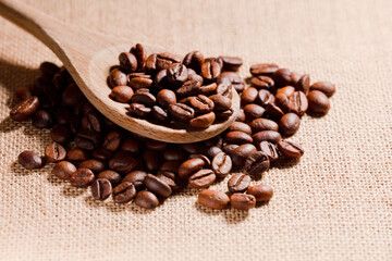 roasted coffee beans on wooden spoon, (selective focus on coffee beans), raffia sack background