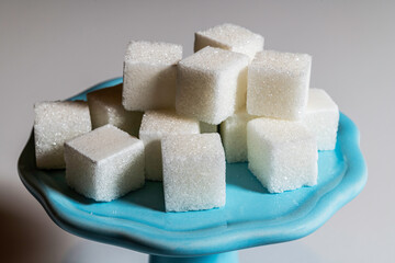 white sugar cubes stacked on blue plate with white background