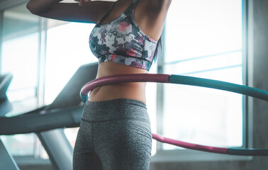 Sporty woman is exercising with Hula hoop in fitness gym for healthy lifestyle concept.