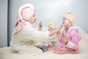 Portrait of woman and her daughters doing doing spa treatments in the bedroom © галина шарапова