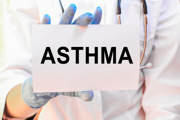 The doctor's blue - gloved hands show the word ASTHMA - . a gloved hand on a white background. Medical concept. the medicine
