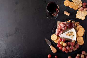 Obraz na płótnie Canvas piece of brie cheese with grapes, crackers and red wine