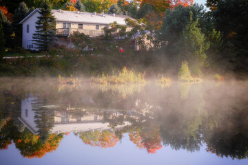Early morning mist burning off a pond with reflections in the water