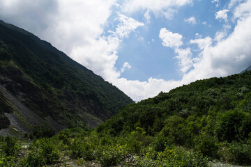Fototapeta premium View of the mountains of the North Caucasus. Karmadon gorge. Mount Kazbek in the clouds. Mountains in the clouds in summer
