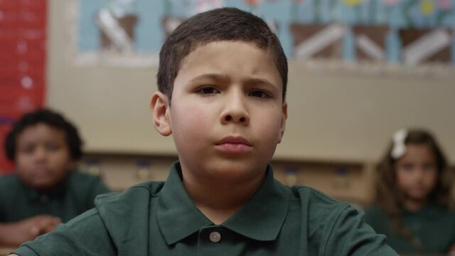 Young hispanic boy looks at the camera with angry look. Student with depression.