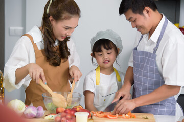 Asian family enjoy with cooking together salad foods homemade in kitchen room at modern home. Create activities together in the family. Soft focus on center children.