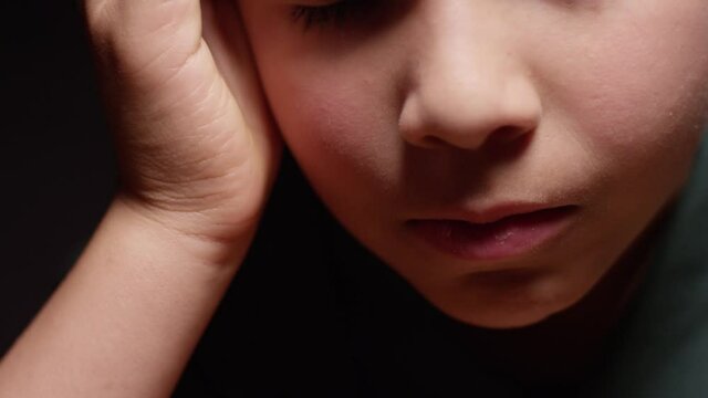 Young hispanic boy sitting at desk in the dark depressed, frustrated, scared