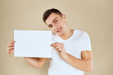 man in white t-shirt sheet of paper in hands Copy Space cropped view beige background