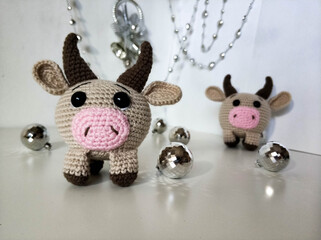 Pair of bulls on white background with Christmas decorations. Crocheted soft toys, handmade. 2021