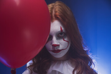 Clown girl with red hair and a red ball in her hands