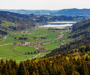 Fototapeta na wymiar Aeria view of lake Großer Alpsee with small village and valley in front a mountains in the background