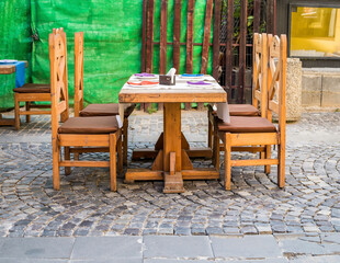 Wooden chairs and table on a cobbled street. Outdoor restaurant in the old town of Bucharest.