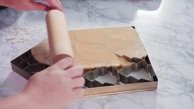 Cutting out sugar cookies with giant Christmas cookie cutter.